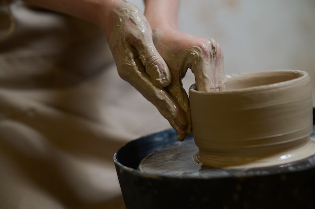 Close up of human hands making a bowl on a pottery wheel