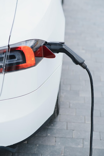 Close up of the Hybrid car electric charger station with power supply plugged into an electric car being charged