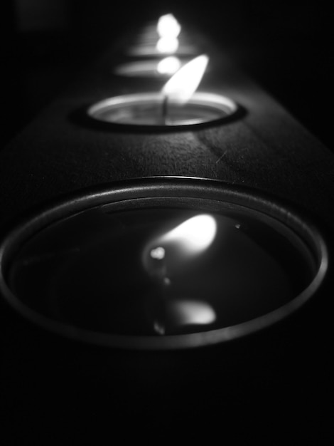 Photo close-up of illuminated candle in dark room