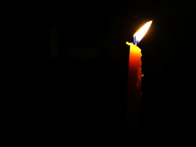 Close-up of illuminated candle in darkroom