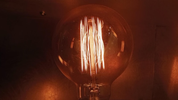 Photo close-up of illuminated light bulb by wall