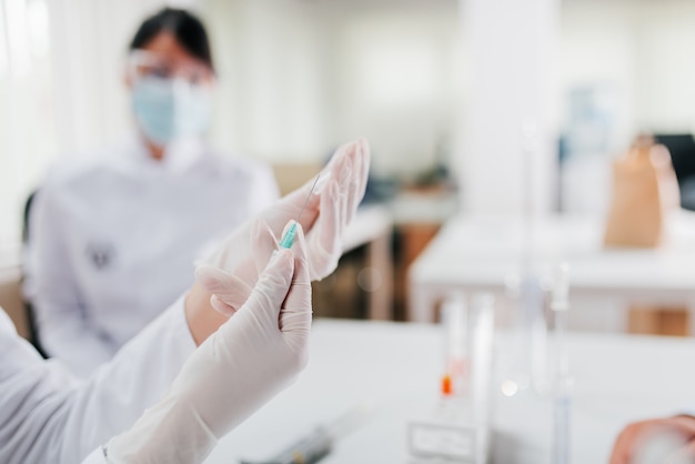 Close-up image of female hand in protective gloves holding suringe.