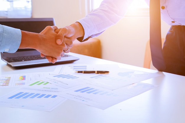 Close-up image of a firm handshake between two colleagues after signing a contract.