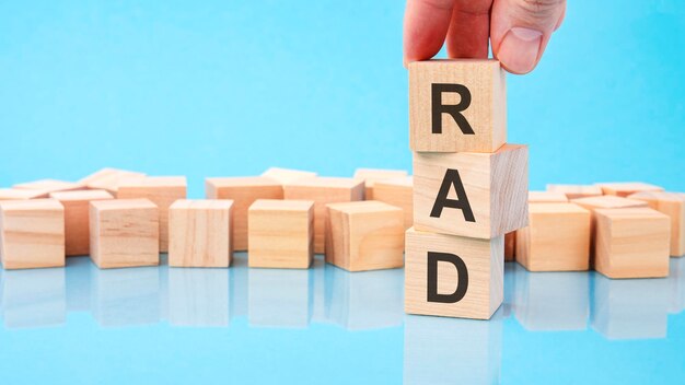 Close up image hand of a young businessman holding a wooden cube with letter r rad on wooden cube on