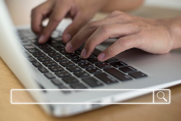 Close up image hand of young businessman use their tying keyboard on laptop to find out what interests them to find ideas about networking and online learning with search bar icon