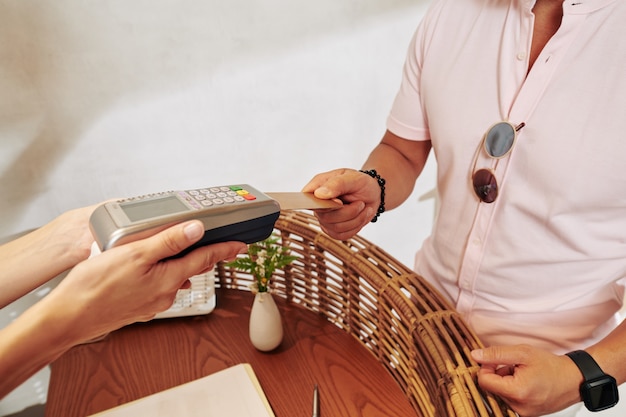 Close-up image of man paying with credit card at hotel reception