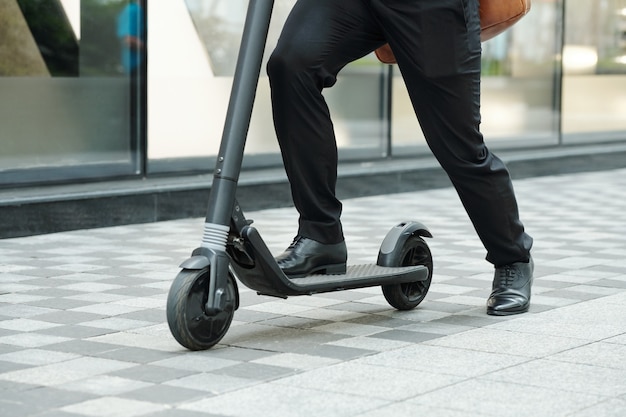 Close-up image of man riding electric scooter when hurrying to work in the morning