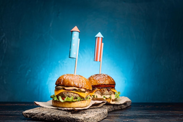 Close up Image of two beef burgers with fireworks rockets. picnic festive snack on the fourth of july independence day