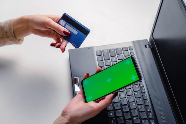 Close up image of woman hands using smartphone blank green screen mockup and holding credit card