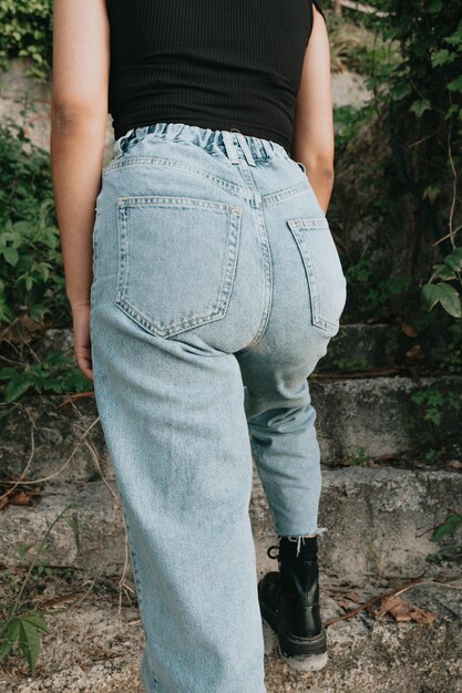 Close up image of a young woman wearing mom jeans going upstairs outdoors Close up image styling and fashion concept with copy space