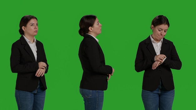 Close up of impatient office worker checking time on wristwatch, standing over isolated greenscreen backdrop. Young woman running late and looking at clock, waiting for something,