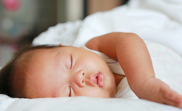 Close up infant baby boy sleeping on the bed.