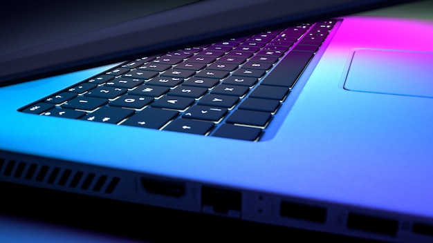 Close up of keyboard laptop with blue pink lighting. Technology concept.