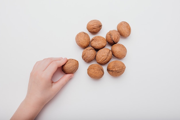 Close up, kid hand with many walnuts isolated on white