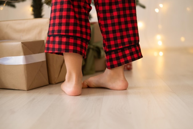 close up kid legs in red Christmas pajama near gift boxes