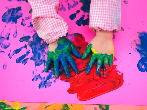 Close up on a kids hand painting with colorful watercolors