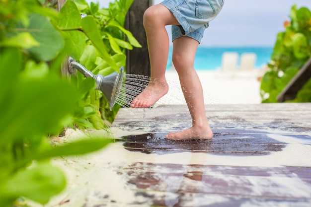 Close up of kids legs under a beach shower