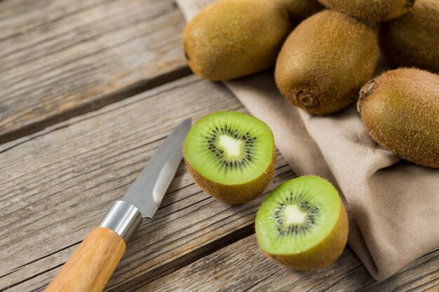 Close-up of kiwis with knife on wooden table