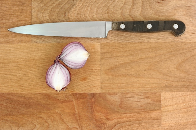 Close up knife with sliced open onion on wooden chopping