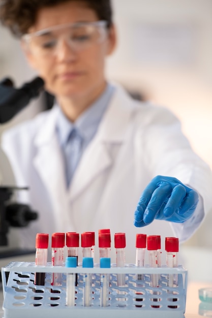 Close-up of laboratory worker in blue gloves sorting blood samples in rack while making tests