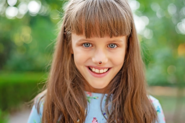 Close-up of a ladybug on the nose of a small shrinking girl. Selective focus of the image.