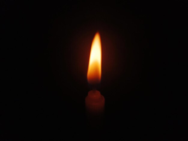 Close-up of lit candle in darkroom