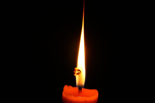 Photo close-up of lit candle in darkroom