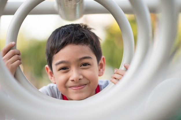 Close up of little boy face hanging on cycle bar at playground