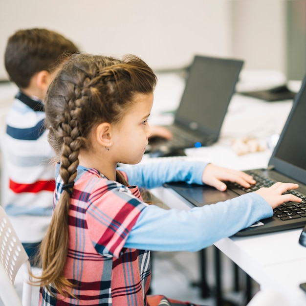 Close-up of little girl using laptop in the classroom