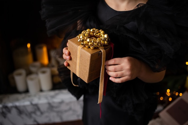 Close up of little girl with Christmas present in her hands near Christmas trees with lights Merry Christmas and Happy Holidays