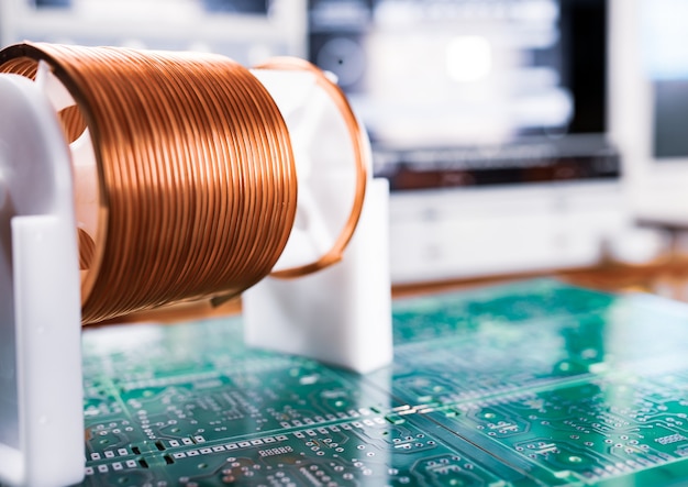 Close-up A lot of skeins of twisted copper wire are standing on a green microcircuit. Factory concept for the production of powerful oscillatory circuit and high-frequency components