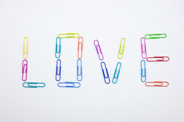 Photo close-up of love text made with colorful paper clips on white background