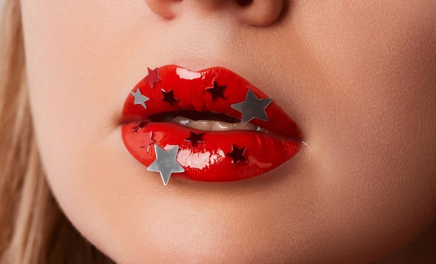 Close up macro womans plump lips with red gloss and silver stars beauty fashion portrait personal ma...