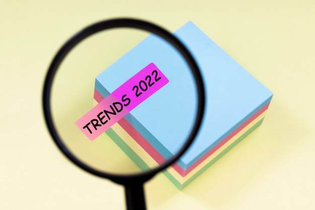 Photo close up magnifier with text trends 2022 on pink sticker on yellow background