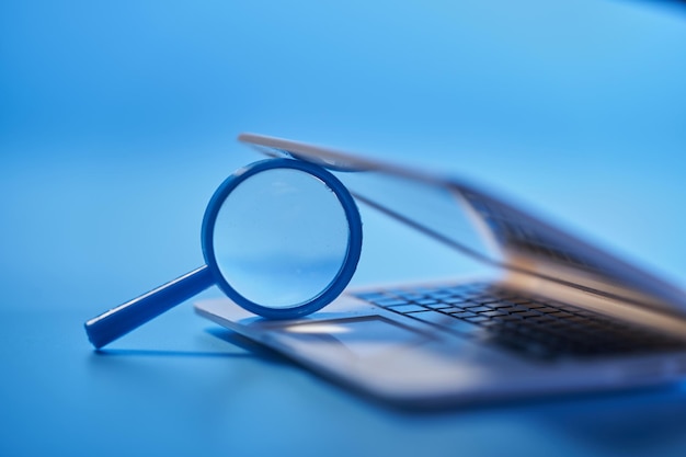 Close up of magnifying glass with small laptop