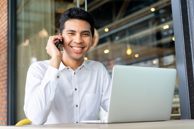 close up malaysian businessman talking business with partner and using laptop at outside office