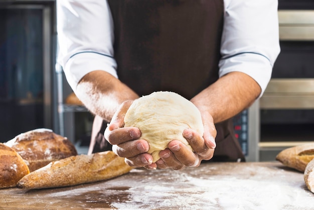 Close-up of a male baker's hand holding freshly kneaded dough