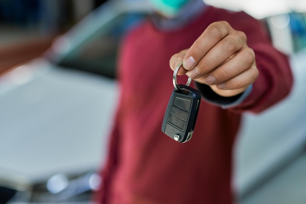 Close up of male customer holding car key in auto repair shop