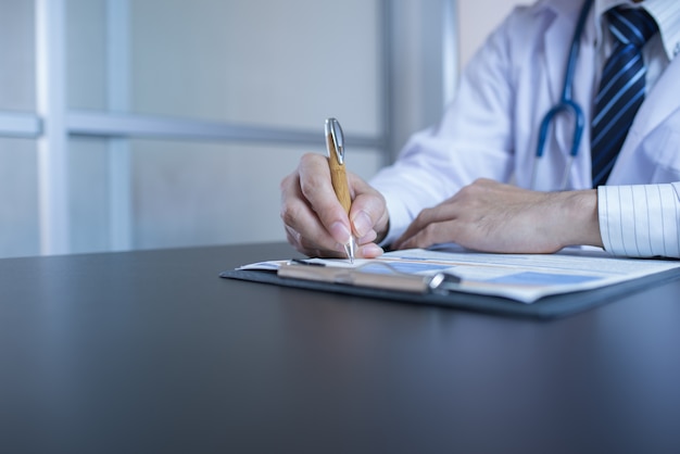 Close-up Of Male Doctor Filling The Medical Form