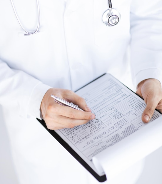 close up of male doctor holding prescription paper in hand