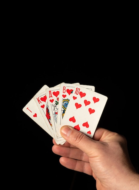 Close up male hand holding Royal Flush cards while playing poker