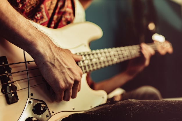 Close up of male hand playing electric guitar in the dark