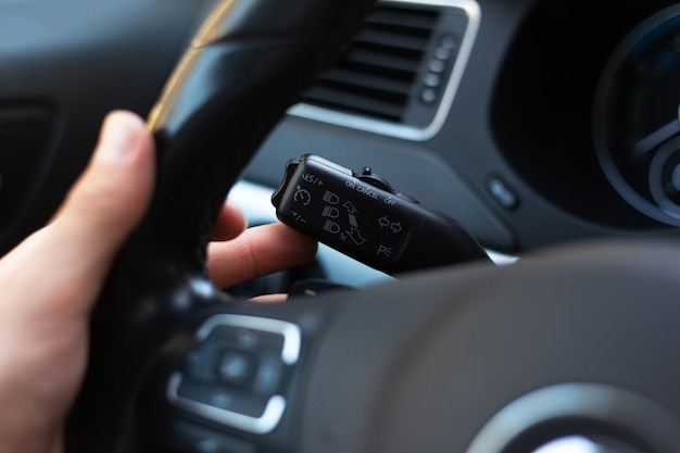 Close-up of male hand, presses signal switch button in the car.