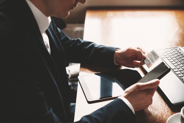 Close up of a male hand using a credit card and a smartphone for online operation in a restaurant .