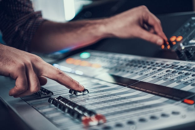 Close up. Male hands adjusting audio controller.