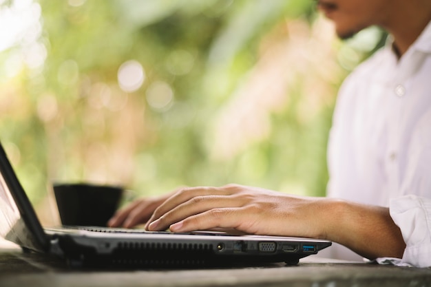 Close up of male hands typing on laptop keyboard background nature