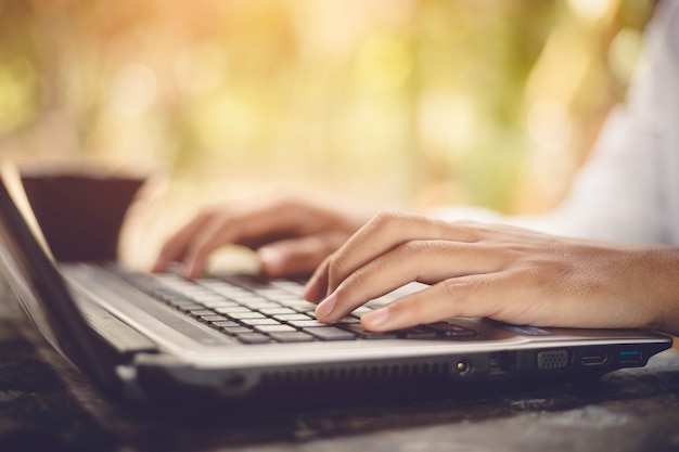 Close up of male hands typing on laptop keyboard background nature