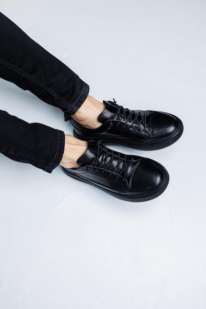 Close up of male legs in black jeans and black leather casual sneakers Comfortable men's demiseason shoes