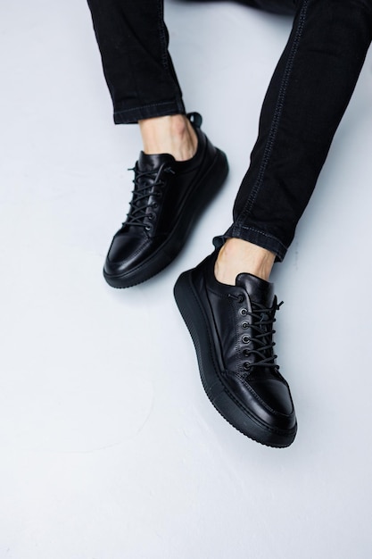 Close up of male legs in black jeans and black leather casual sneakers Comfortable men's demiseason shoes