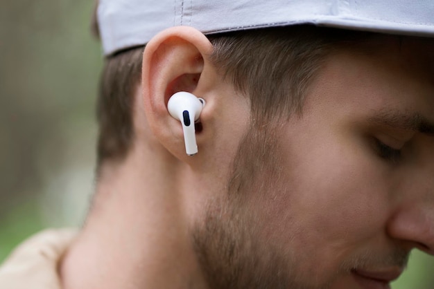 A close up male person using wireless earphones and listen to the music